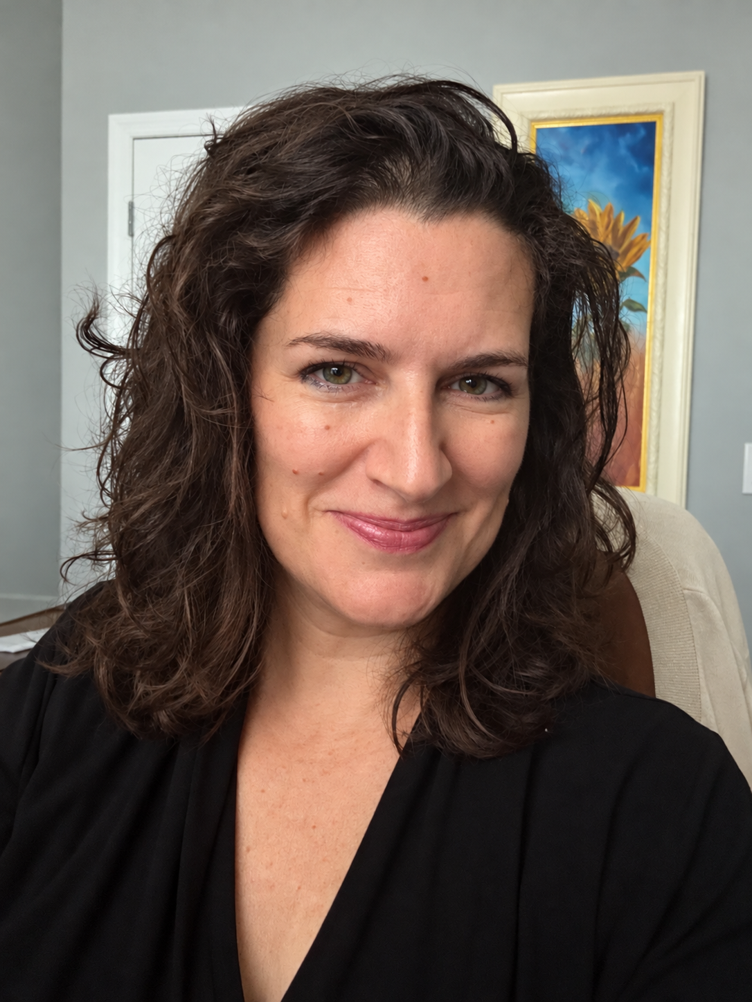 Jessica Gaffney smiling at home, with a sunflower painting behind her